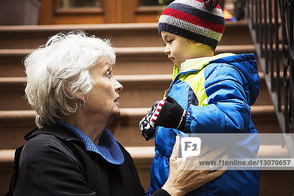 Großmutter unterhält sich mit einem Jungen  während sie auf einer Treppe sitzt