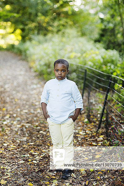 Portrait of boy with hands in pockets standing in park