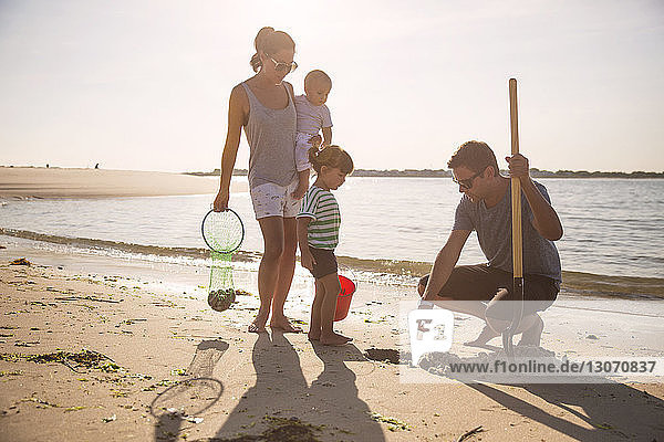 Familie sucht am Strand am Meeresufer vor klarem Himmel