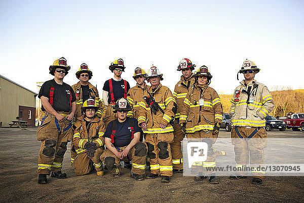 Porträt von selbstbewussten Feuerwehrmännern in der Feuerwache vor klarem Himmel
