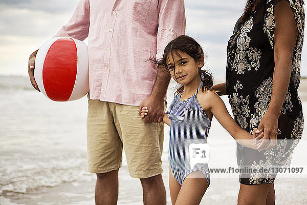 Porträt eines Mädchens  das mit den Eltern am Strand spazieren geht