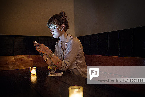 Frau benutzt Smartphone  während sie in einer Bar sitzt