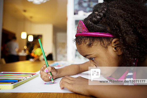 Close-up of girl drawing on paper at table in living room