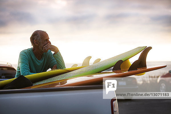 Älterer Mann mit Surfbrettern im Auto