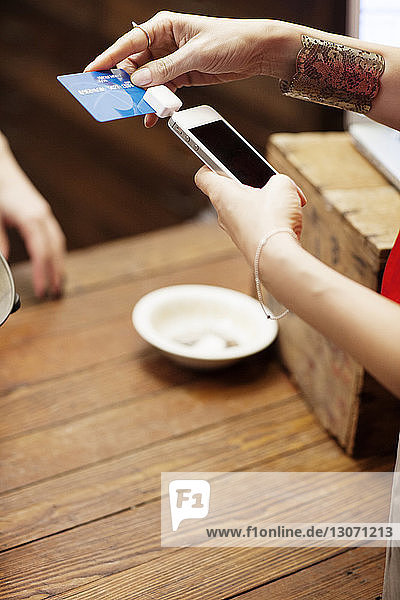 Ausgeschnittenes Bild einer Frau  die ein Kreditkartenlesegerät zum Bezahlen benutzt