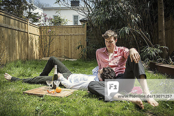 Gay couple relaxing on field in backyard