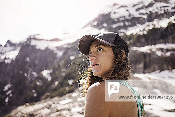Woman looking away while standing against mountain