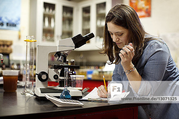 Frau arbeitet mit dem Mikroskop am Tisch in einer Brauerei