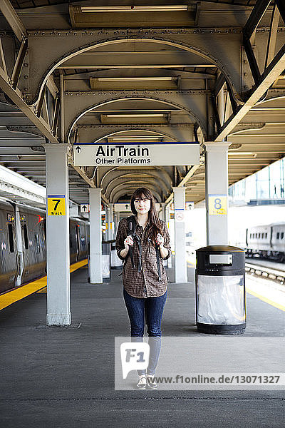 Woman with backpack standing on railroad station