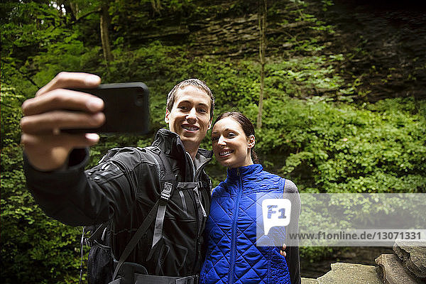 Couple taking selfie while standing in forest