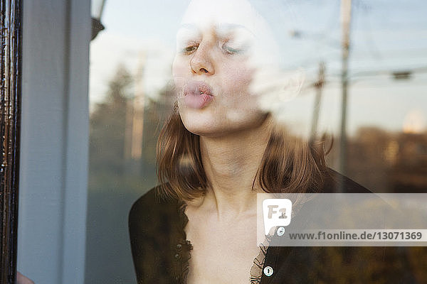 Frau kräuselt sich beim Stehen am Glasfenster