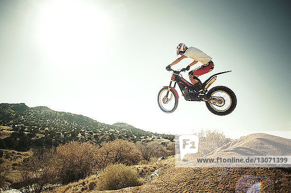 Seitenansicht eines Mannes  der vor klarem Himmel einen Stunt mit einem Motorrad macht