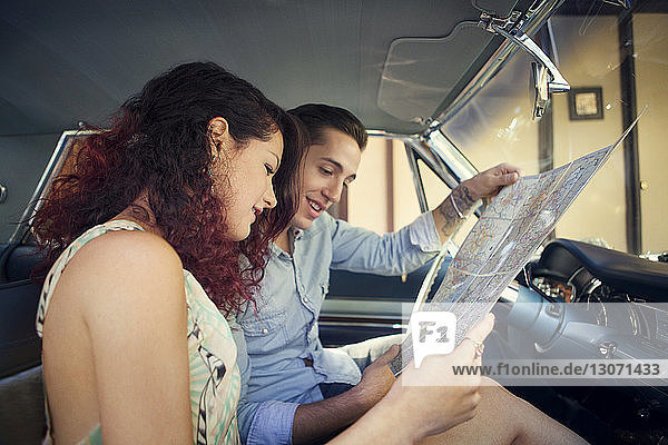 Ehepaar schaut auf die Karte  während es in einem Oldtimer sitzt