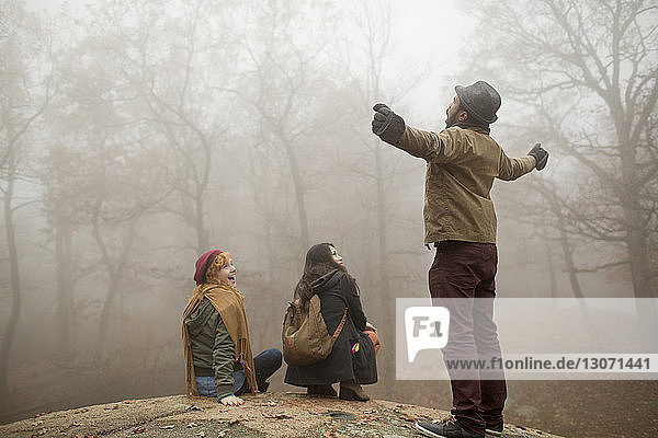 Friends looking at man shouting while standing in forest