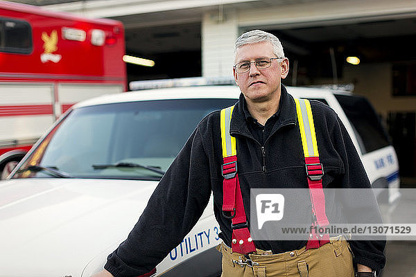 Portrait of firefighter leaning on car at fire station