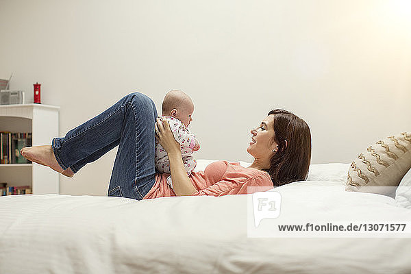 Woman playing with daughter while lying on bed