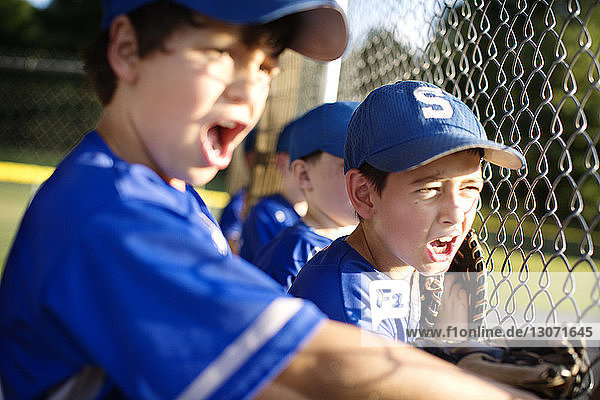 Boys cheering while standing in dugout