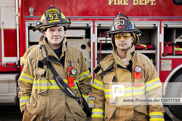 Porträt von Feuerwehrleuten  die gegen ein Feuerwehrauto stehen