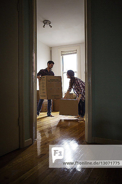 Ein Paar  das Kisten in seinem neuen Zuhause trägt  durch die Tür