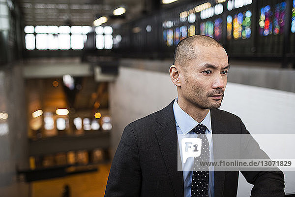Thoughtful businessman looking away while standing at railroad station