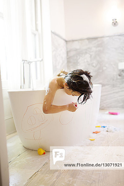 Boy drawing on bathtub while bathing
