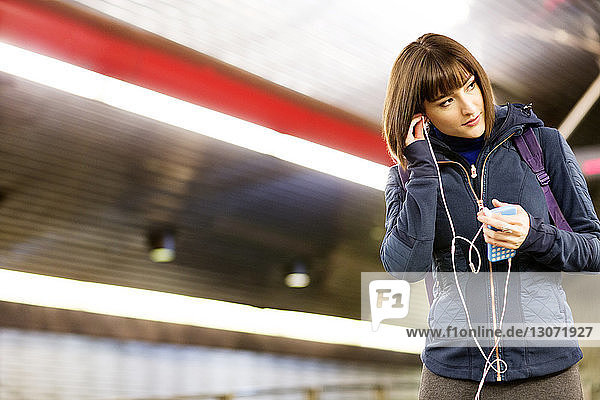 Frau hört Musik  während sie in der U-Bahn-Station steht