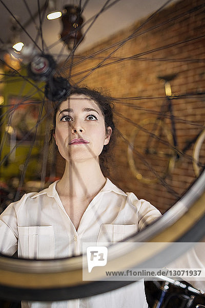Frau betrachtet Fahrradrad  während sie in der Werkstatt steht