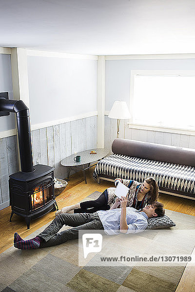 High angle view of couple using tablet computer at while lying on floor at home