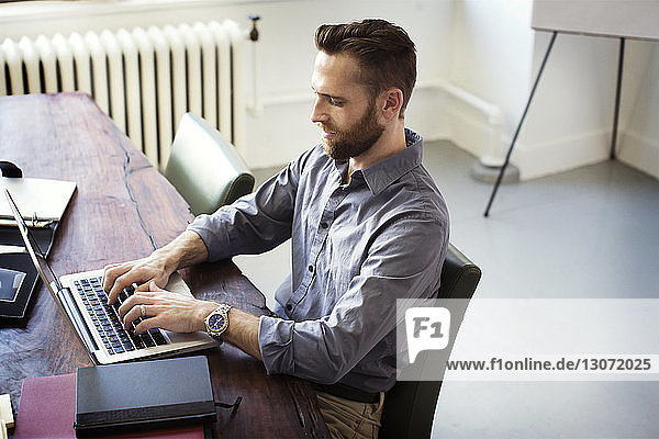 High angle view of man using laptop computer while sitting in office
