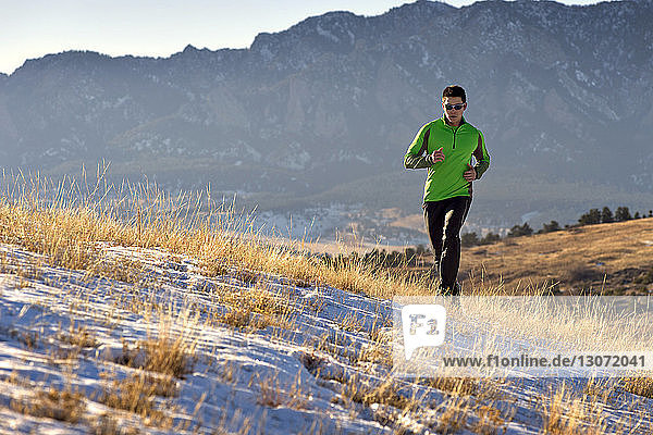 Mann joggt auf Feld gegen Berge