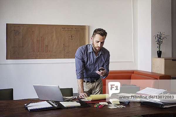 Mann benutzt Smartphone bei der Arbeit im Büro