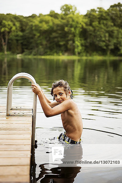Porträt eines Jungen im See auf dem Geländer am Dock