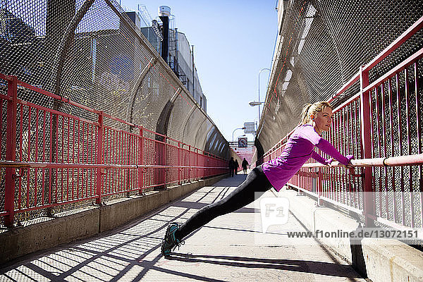 Seitenansicht einer Frau  die an der Fußgängerbrücke Williamsburg Bridge trainiert