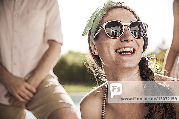Glückliche Frau mit Sonnenbrille an einem sonnigen Tag im Hinterhof