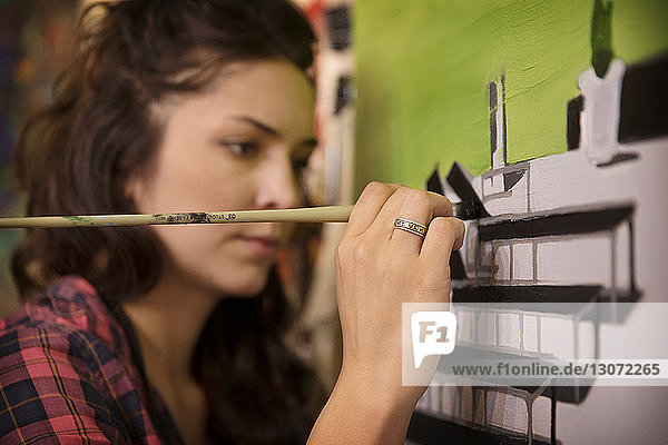 Nahaufnahme einer seriösen Frau  die zu Hause an die Wand malt