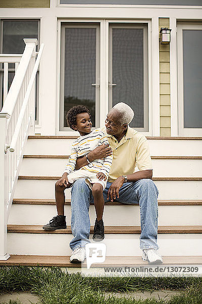 Großvater und Enkel unterhalten sich im Sitzen auf Stufen