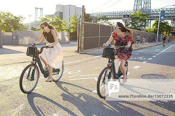 Happy friends riding bicycle on city street