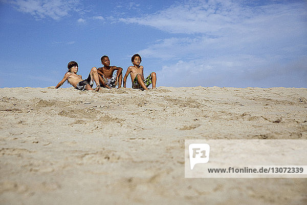 Jungen entspannen sich auf Sand gegen den Himmel