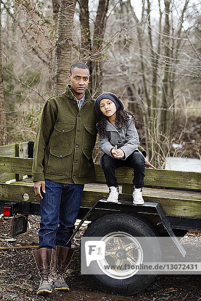 Portrait of daughter sitting on vehicle with father