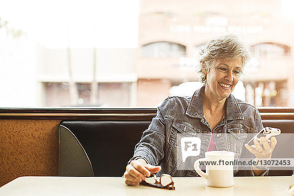 Frau benutzt Mobiltelefon  während sie im Café sitzt