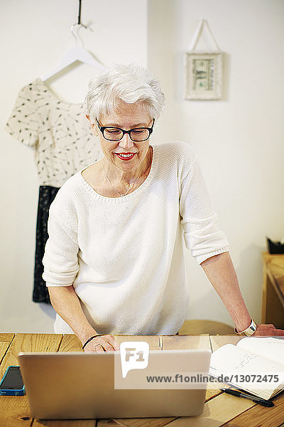 Senior woman using laptop computer while working in boutique store
