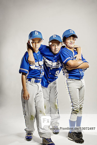 Portrait of confident baseball players standing against white background