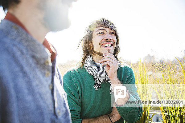 Glücklicher Mann steht mit männlichem Freund während Gartenparty im Hof