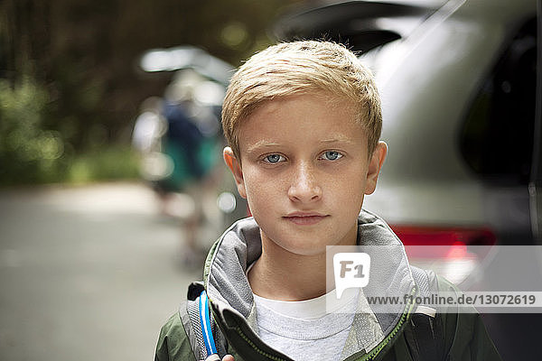 Porträt eines süßen Jungen mit Rucksack gegen Auto