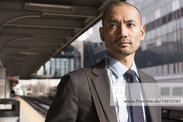 Man looking away while standing at railroad station