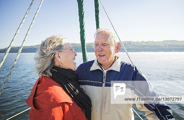Cheerful senior woman standing with man in yacht on sea