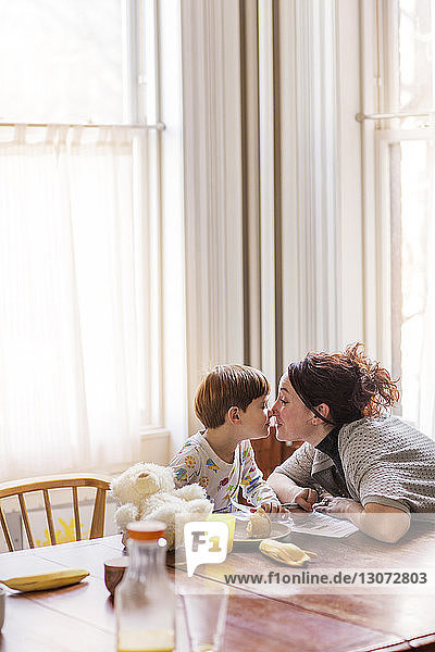 Mutter und Sohn reiben sich die Nase  während sie zu Hause am Tisch sitzen