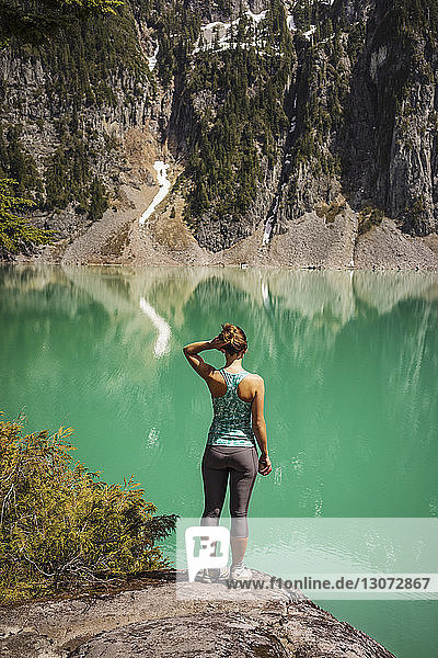 Rear view of woman standing on mountain against lake