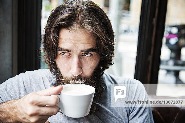 Close-up of man with beard drinking coffee while sitting at cafe