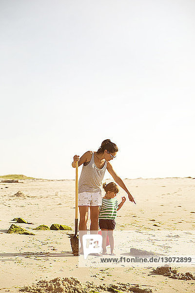 Mutter zeigt Tochter  die am sonnigen Tag am Meeresufer geht
